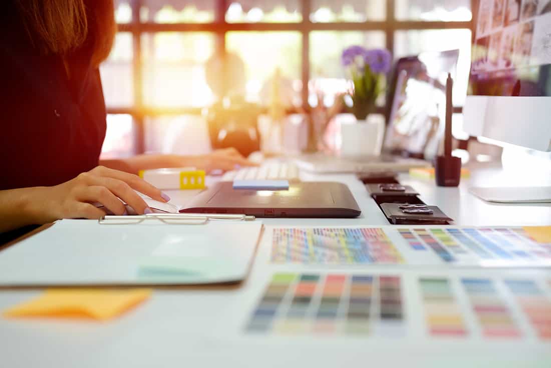 Designerin am Arbeitsplatz mit Farbmustern und Skizzen